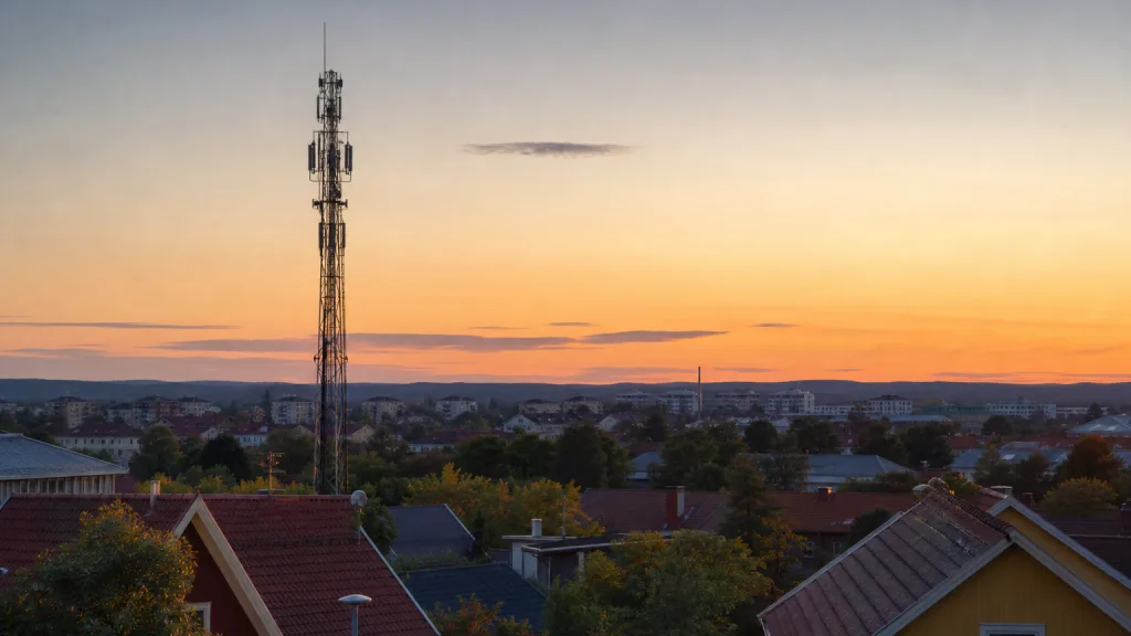 Mobilmast mot en svensk stadssiluett i kvällsljus
